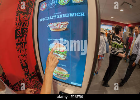 Diners order at a 'Create Your Taste' kiosk at a McDonald's in New York on Tuesday, August 4, 2015. The interactive iPad-like digital displays allow customers to customize their order with toppings, new sauces, etc. and have them delivered to their table in a few minutes. McDonald's, which has seen same-store sales drop over three years, is using the kiosks to compete with fast casual restaurants such as Chipotle, Fatburger and a host of others. (© Richard B. Levine) Stock Photo