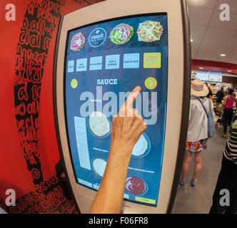 Diners order at a 'Create Your Taste' kiosk at a McDonald's in New York on Tuesday, August 4, 2015. The interactive iPad-like digital displays allow customers to customize their order with toppings, new sauces, etc. and have them delivered to their table in a few minutes. McDonald's, which has seen same-store sales drop over three years, is using the kiosks to compete with fast casual restaurants such as Chipotle, Fatburger and a host of others. (© Richard B. Levine) Stock Photo