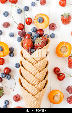 Fruits in the ice cream cone with from above on white wooden background Stock Photo