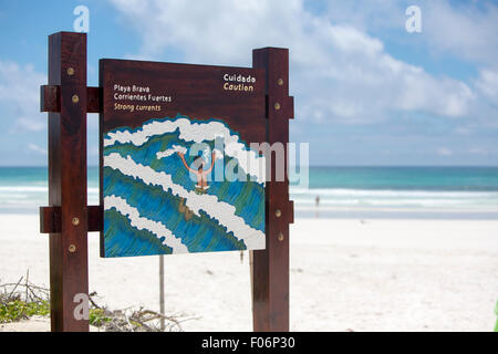 Warning sign at Tortuga Bay beach near Puerto Ayora against a blue cloudy sky in the Galapagos Islands. Ecuador 2015 Stock Photo