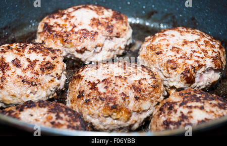 Six thick juicy beef hamburgers frying in pan closeup Stock Photo