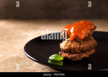 Roasted meatballs with tomato sauce in dark plate Stock Photo