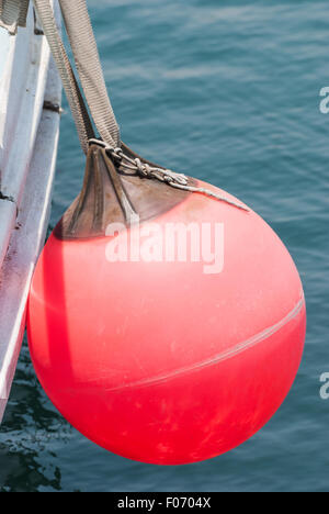 Red buoy hanging on the aboard of fishing boat. Close-up Stock Photo