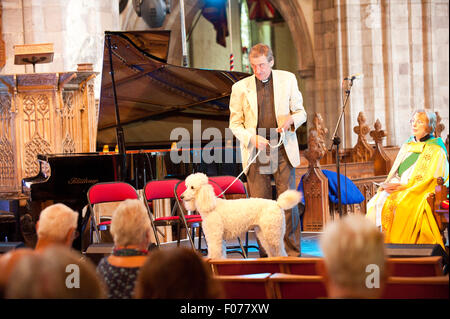 Brecon, Powys, UK. 9th August 2015. Deacon Judy Day  and The Very Rev'd Dr Paul Shackerley look on as Pianist Father Richard Williams brings his poodle Daisy to the altar before performing a jazz piano piece during the Cathedral Jazz Festival Service. The 31st Brecon Jazz Festival takes place in the beauty of the Brecon Beacons and this year boasts the most international line-up in the event’s 31 year history. Headliners are Ray Davies, Dr. John, and Robert Glasper. The Brecon Fringe Festival also takes place on the same dates in various venues throughout the town. © Graham M. Lawrence/Alamy L Stock Photo