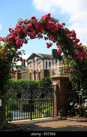 A rose arch within the gardens of Kensington Palace, London, with the palace in the background (background in focus alt: F078YR) Stock Photo
