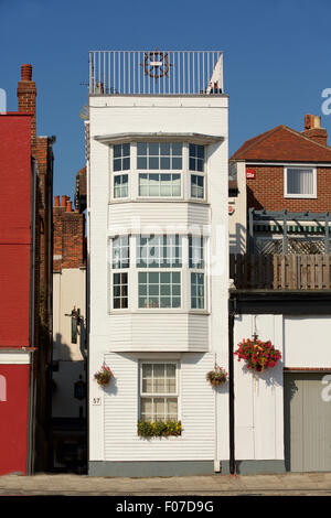 Lovely narrow house on Spice Island in Old Portsmouth. White wooden building with a ships wheel on the top balcony. Stock Photo