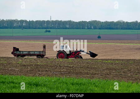 Ploughing field in spring. Tractor with trailer, Zavet town, Bulgaria Stock Photo