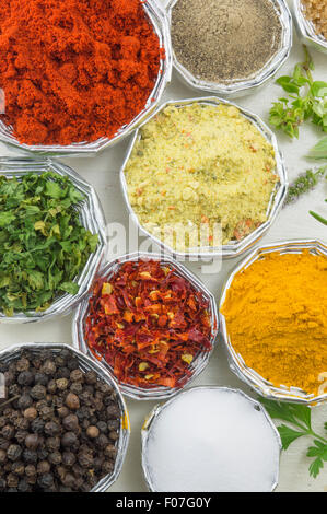 Close-up of various spices in shiny bowls on a white wooden table Stock Photo