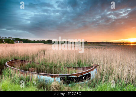 Sunrise over an old fishing boat in reeds at Hamworthy in Poole, Dorset Stock Photo
