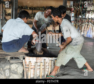 Blacksmiths shape red-hot steel blade at anvil in Sei Kaune village on Inle Lake, Shan State, Myanmar Stock Photo
