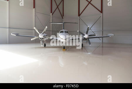 Small two-propeller aircraft parked in a big hangar Stock Photo