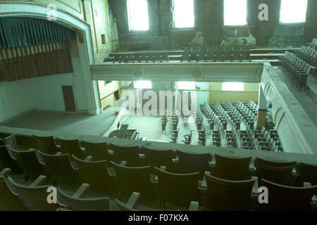 Stage and rows of seats inside abandoned school auditorium in sunlight. Stock Photo