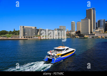 Manly Fast Ferry (Ocean Rider) is speeding across Sydney harbour toward Circular Quay ferry dock on a sunny day. Stock Photo