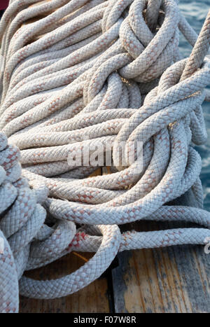 Coiled rope lines stored on belaying pins Stock Photo