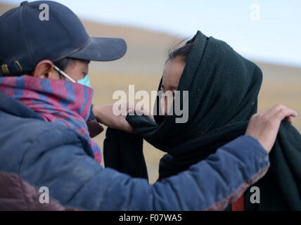 (150810) -- NYIMA, Aug. 10, 2015 (Xinhua) -- Husband helps mailwoman Bamu to wrap up in Nyima County of Nagqu Prefecture, southwest China's Tibet Autonomous Region, June 11, 2015. Bamu, a 26-year-old woman of Tibetan ethnic group, has been working as a mailwoman since 2006 for seven remote villages in Nyima County, which stands at an average of 4,500 meters above sea level and covers over 150 thousand square kilometers but has a population of less than 30 thousand. The farthest village is more than 100 kilometers away from the county town, and even some door-to-door distance in the Stock Photo