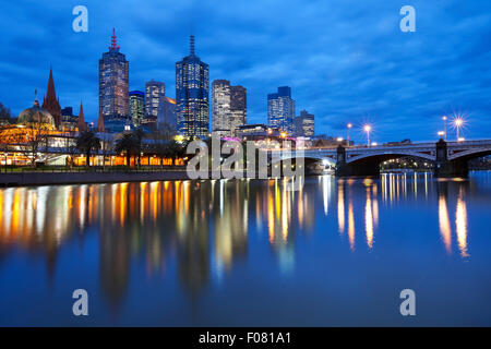 The skyline of Melbourne, Australia with Flinders Street Station and the Princes Bridge from across the Yarra River at night.