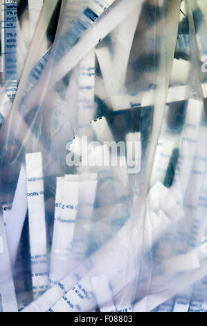 Securely shredded paper seen through the side of a transparent plastic bag. Stock Photo