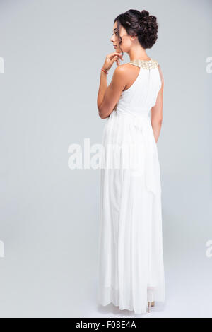 Back view portrait of a young woman standing in trendy dress on gray background Stock Photo
