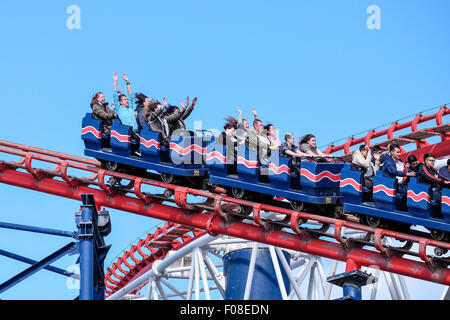 People riding The Big One at Blackpool Pleasure Beach with their hands held aloft on a summer's day with blue sky. Stock Photo