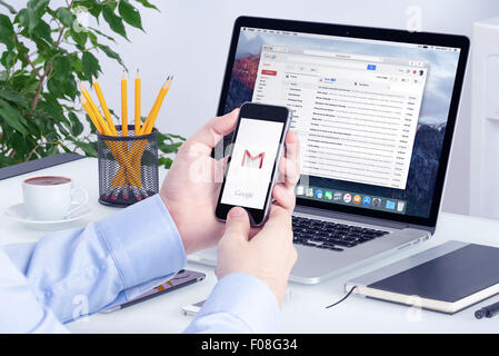 Varna, Bulgaria - May 29, 2015: Gmail app on the iPhone display in man hands and Gmail desktop version on the Macbook screen. Stock Photo