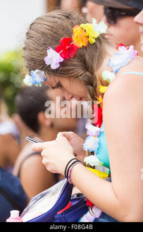 Young woman using mobile phone at festival, oblivious to the loud music and crowds of people. Stock Photo
