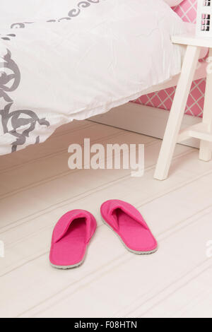 Pink slippers under the bed in bedroom Stock Photo