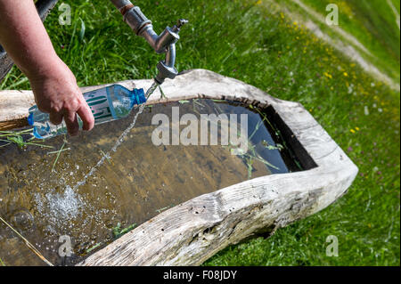 Filling plastic water bottle from a tap fed from a mountain stream in the Austrian Mountains. Stock Photo