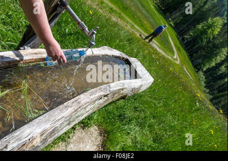 Filling plastic water bottle from a tap fed from a mountain stream in the Austrian Mountains. Stock Photo