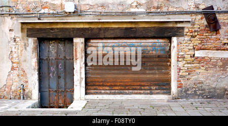 old and rustic metal doors with decay brick wall building in Venice, Italy Stock Photo