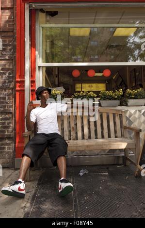 Man relaxing outside Pizza shop in New York, USA Stock Photo