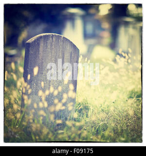 Tombstone and graves in an ancient church graveyard with Instagram style filter effect Stock Photo