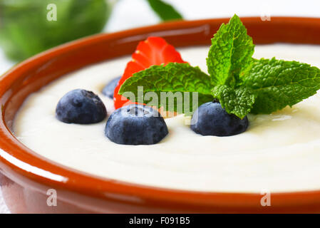 Smooth semolina porridge served in terracotta dish with fresh fruit Stock Photo
