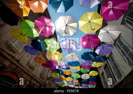 A sea of Brightly coloured floating umbrellas fill the sky above Rue Jean Jaures in Arles, Provence, South of France. Stock Photo