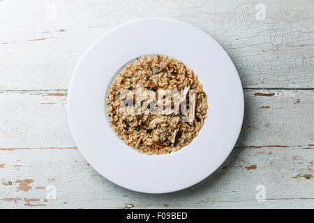 Risotto with wild mushrooms cep boletus on white plate on blue wooden background Stock Photo