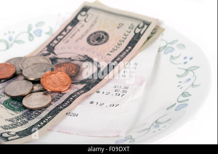 Restaurant bill with dollar bills (tips) on a plate and receipt isolated on a white background Stock Photo