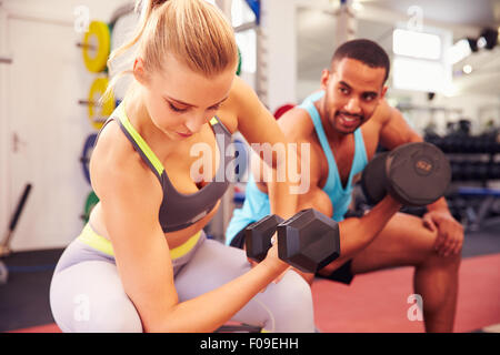 Man and woman exercising with dumbbells at a gym Stock Photo