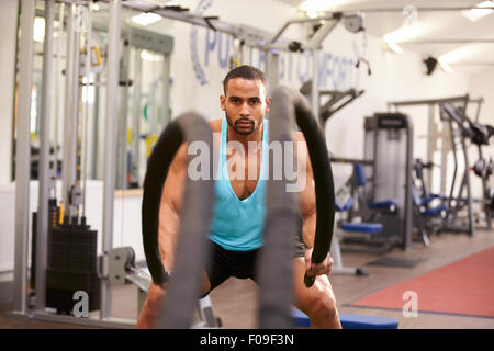 Young man working out with battle ropes at a gym Stock Photo