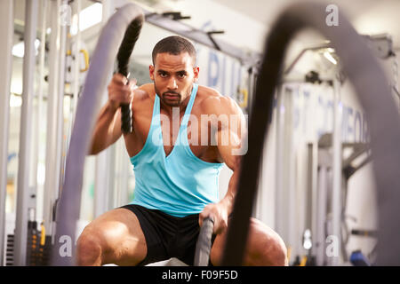 Young man working out with battle ropes at a gym Stock Photo