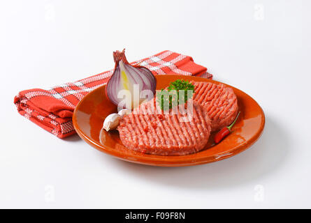 two raw hamburger patties on plate Stock Photo