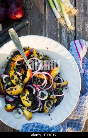Bowl with lentil and fruit salad on a wooden garden table with kitchen towel. Top view Stock Photo