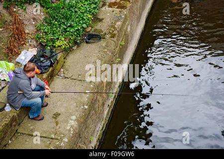 Man fishing in river Aire in central Leeds, West Yorkshire, UK Stock Photo