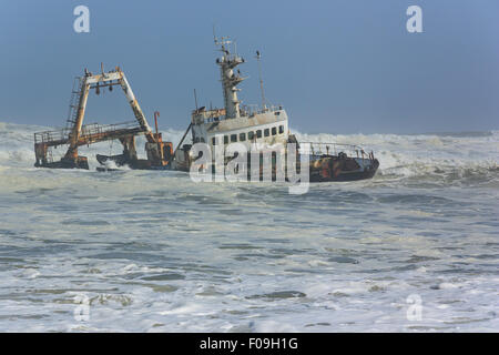 Shipwreck of a fishing trawler eroding in the waves close to the shore. Stock Photo