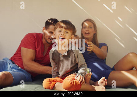 Happy little boy sitting on patio with his family at the back. Focus on little boy sitting in front with his parents and sister Stock Photo