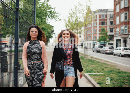 Outdoor shot of two girlfriends walking through town. Happy young women walking together along a city street.
