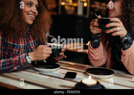 Cropped shot of a young friends in a coffee shop. Young women in cafe sitting at table drinking coffee Stock Photo