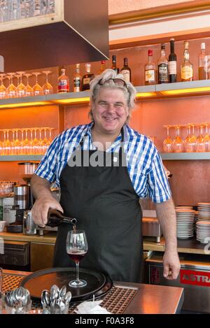 Portrait of Christoph Elbert pouring wine in glass at kitchen, Linden, Hannover, Germany Stock Photo