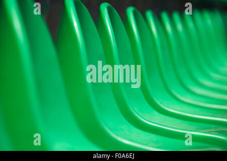 Empty green plastic stadium seats arranged in a row. The image has been made before the beginning of a tennis game. Stock Photo