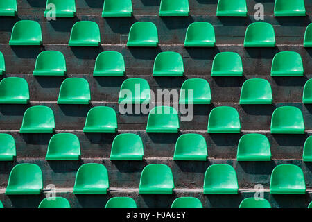 Image of green plastic stadium seats in rows. The seats are filled the frame as background. This is a day shot of an empty stadi Stock Photo