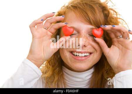 Happy woman holding heart shaped candy in front of her eyes Stock Photo