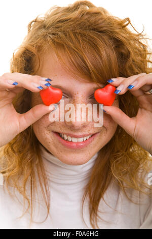 Happy woman holding heart shaped candy in front of her eyes Stock Photo
